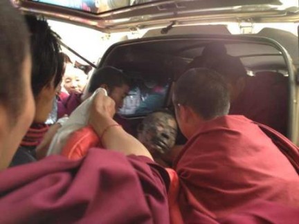 阿旺諾培因嚴重燒傷，被當地僧人抬上車準備送往醫院救治。 